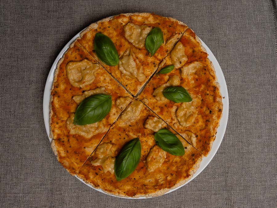 Szeletekre vágott gluténmentes Margherita pizza friss bazsalikommal tányéron