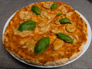 Gluténmentes Margherita pizza bazsalikommal, szeletelve, fehér tányéron